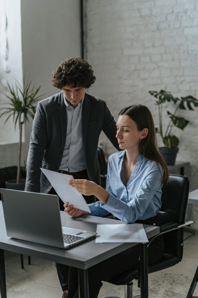 pexels photo 5313156 5313156 Two professionals in an office setting reviewing documents on a laptop.