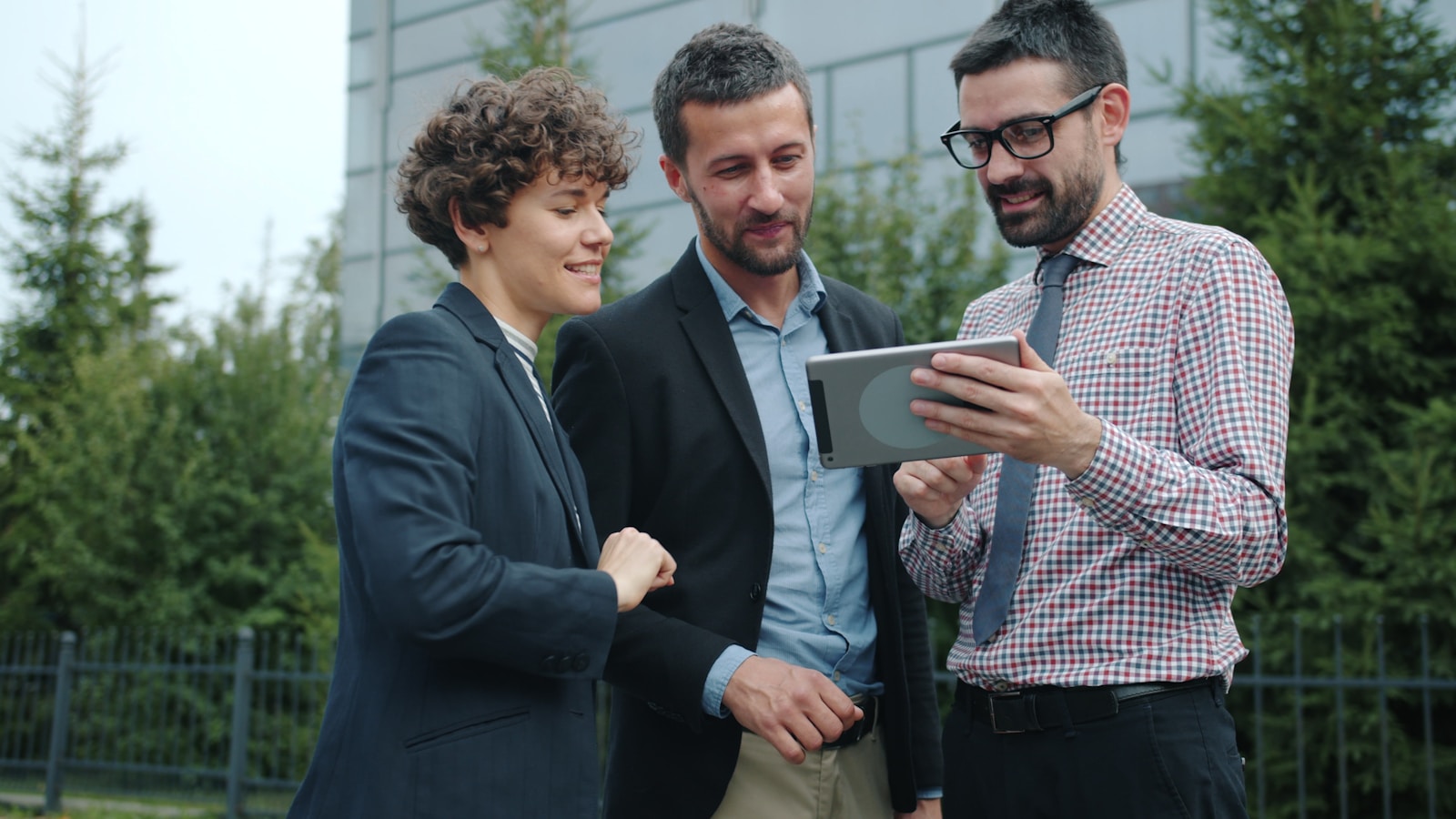 Accompagner la transition numérique pour les managers Three business people looking at a tablet outside.